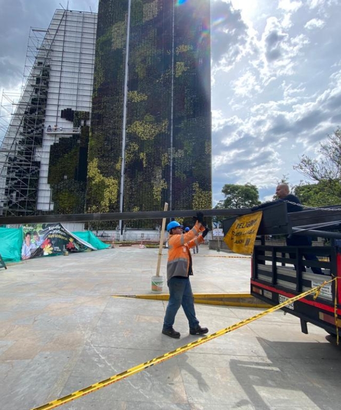 Persona con implementos de seguridad descargando tubería en acero de un camión. Al fondo se visualiza un edificio moderno en construcción y un cielo abierto.